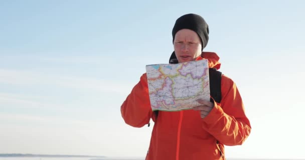 Ο ταξιδιώτης κοιτάζει τον χάρτη και επιλέγει τη διαδρομή πεζοπορίας σε βουνά από χιόνι. — Αρχείο Βίντεο