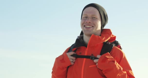 Voyageur homme en vêtements chauds avec sac à dos regarde caméra et sourire . — Video