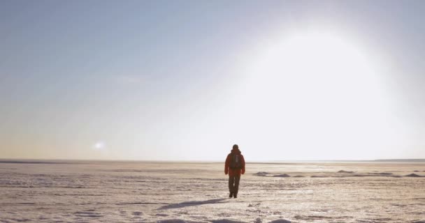 Uomo viaggiatore sta camminando su una zona innevata in montagna, va lontano . — Video Stock