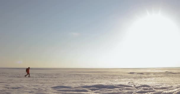 Człowiek podróżnik jest chodzenie na śniegu pokryte obszar w górach. Widok z daleka. — Wideo stockowe