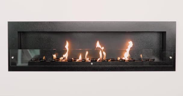 白い壁の部屋の内部の黒い石が付いている装飾的な人工暖炉。クローズアップ暖炉. — ストック動画