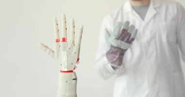 Bilim adamı, elinde sensörlerle ellerinin hareketini tekrarlar robotik protez el test ediyor. Kas reennervation teknolojisi.