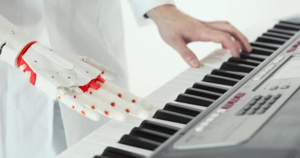 Вчений-інженер дегустує роботизований протез, граючи на піаніно. Граючи дві руки, роботизована протезна рука і людська рука . — стокове відео