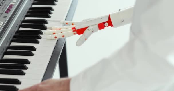 L'ingegnere scientifico sta suonando il pianoforte con la mano robotica della protesi. Giocare due mani, una mano robotica protesica e una mano umana . — Video Stock