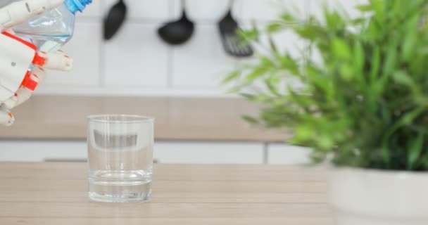 Tangan palsu Robotic menuangkan air dalam gelas dari botol di dapur . — Stok Video