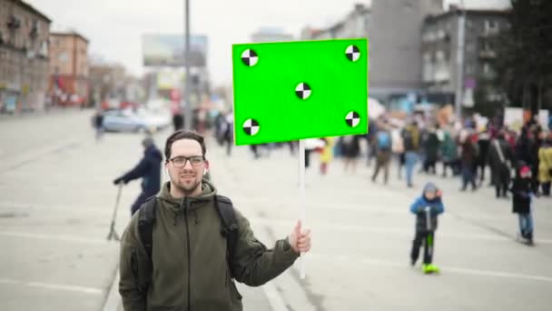 Felice giovane sulla manifestazione della città tiene poster con lo schermo verde in mano . — Video Stock