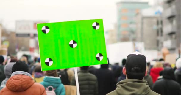 남자는 녹색 화면으로 큰 포스터를 들고 도시 집회, 백 뷰에 군중과 함께 거리를 걷고. — 비디오