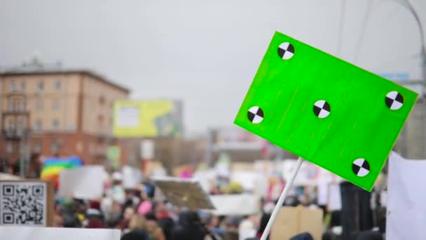 Plakat mit grünem Schirm auf Holzstab schwankt vor Menschenmassen-Hintergrund von Seite zu Seite. — Stockvideo