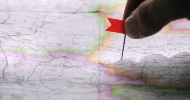 Homem está escolhendo um lugar para viagem colocando pino de bandeira vermelha em um mapa aleatoriamente . — Vídeo de Stock