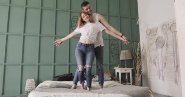 Genç romantik çift yatakta dans edip sarılıyor. İlişki ve aşk kavramı.