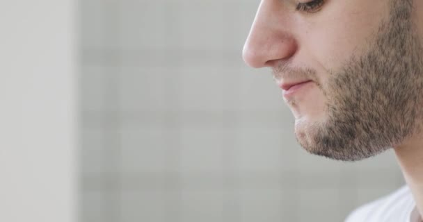 Young man is eating burger at home, mouth closeup, side view. — Stockvideo