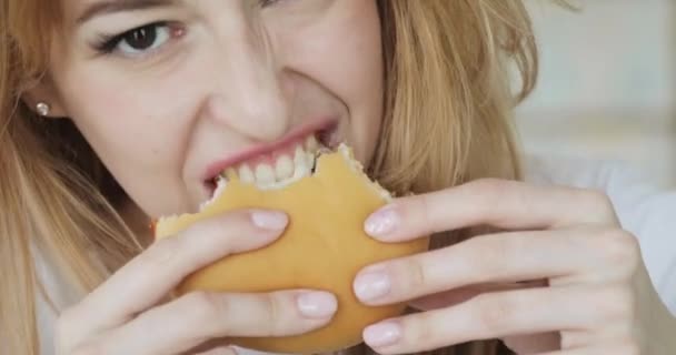 Κοντινό πλάνο της νεαρής γυναίκας δάγκωμα και μάσημα Burger. — Αρχείο Βίντεο
