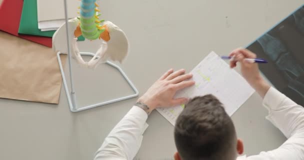 Le docteur fait sa paperasse, remplit la table assise au bureau de la clinique. . — Video