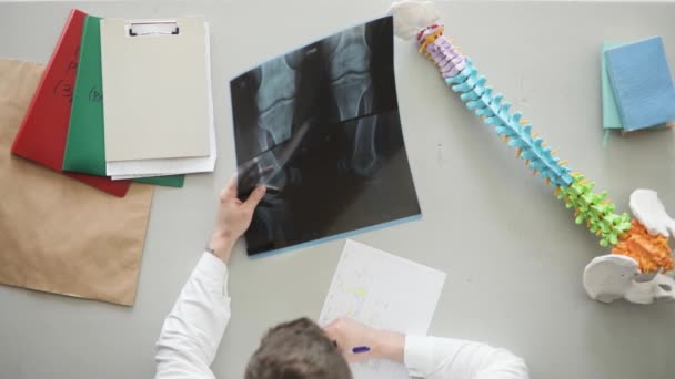 Roentgenologist médecin remplit le blanc avec la description de l'image de rayons X assis à son lieu de travail . — Video