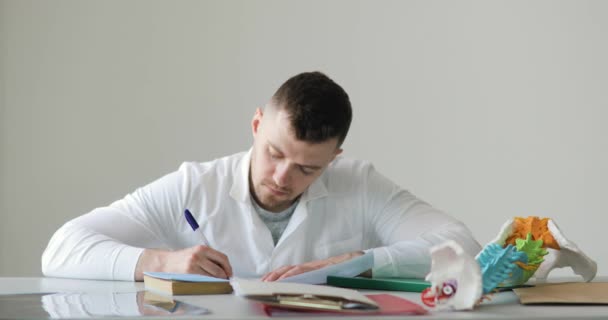 Retrato de roentgenologist está haciendo su documentación escribiendo descripción de roentgen sentado en su lugar de trabajo . — Vídeos de Stock