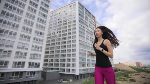 Mujer joven corriendo en la ciudad con modernos edificios de pisos de muti en cámara lenta . — Vídeo de stock