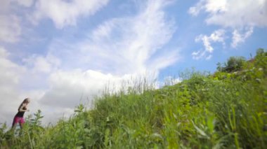 Genç kadın gökyüzü arka plan üzerinde tepeye yükselterek kros alanında koşu.