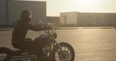 Motosiklet li adam bisikletçi güzel gün batımı ışık şehirde yolda sürme.