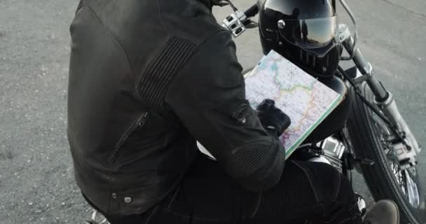 Hombre irreconocible motorista elige la ruta en el mapa sentado en su bicicleta . — Vídeo de stock