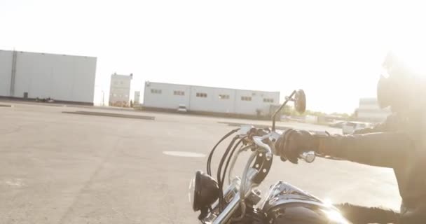 Hombre motociclista monta una motocicleta en la carretera en la ciudad al atardecer, vista lateral . — Vídeos de Stock