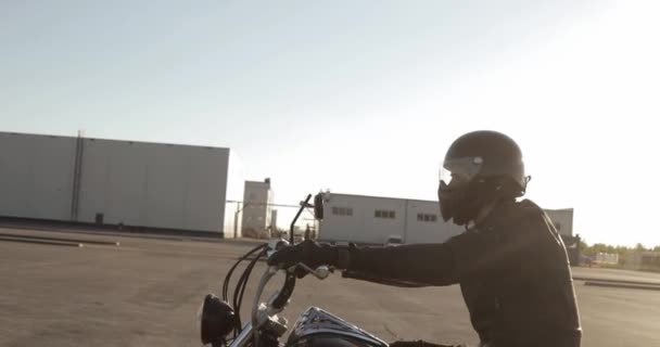 Motociclista uomo guida una moto sulla strada al tramonto in città, vista laterale . — Video Stock