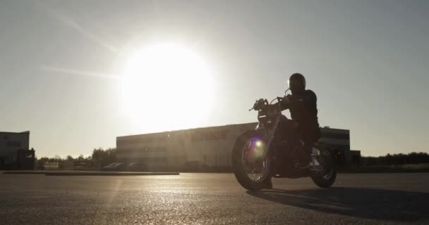 Silhouette de motard homme sur la moto roule sur la route en ville au coucher du soleil . — Video