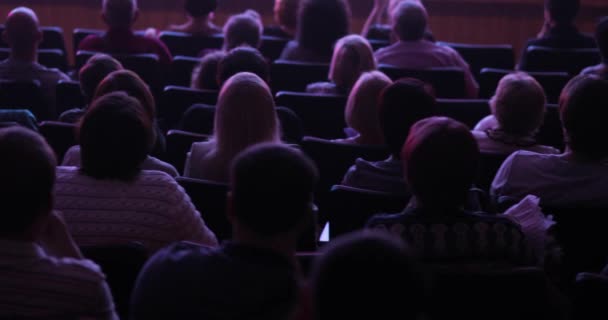 Глядачі спостерігають за постановкою на театральній сцені, сидячи в аудиторії, вид ззаду . — стокове відео