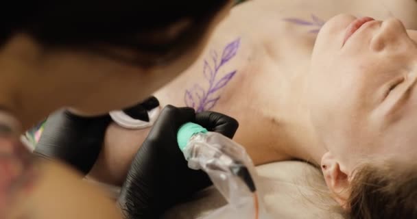 Tatuaggio artista facendo tatuaggio con foglie in studio per giovane donna, primo piano . — Video Stock