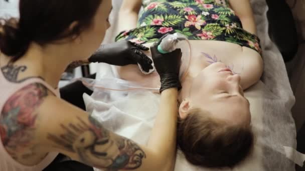 Tatuagem artista fazendo tatuagem com folhas no estúdio para jovem, vista superior . — Vídeo de Stock