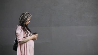 Mutlu genç hamile kadın hipster kahve ile şehirde sokakta yürürken.