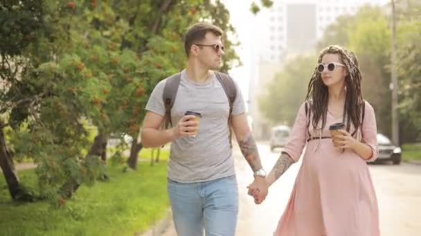 Happy couple man and pregnant woman walking together in city holding hands. — Stock Video