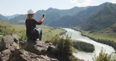 Kadın gezgin blogger dağda oturan telefonda blog için içerik çekim.