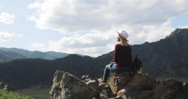 Mujer viajero se sienta en la cima de la montaña admira la vista de la naturaleza con el río en el valle . — Vídeo de stock