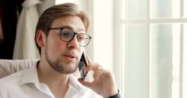 Akıllı telefondan konuşan işadamının portresi pencerenin yanında oturuyor..