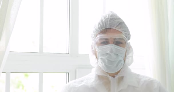Πορτρέτο του ανθρώπου γιατρός βγάζει προστατευτική μάσκα, γυαλιά, κουκούλα σε πανδημία. — Αρχείο Βίντεο