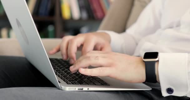 Mani dell'uomo in camicia bianca che digita sul computer portatile tenendolo in ginocchio in ufficio . — Video Stock