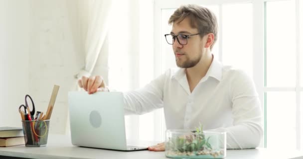 Młody człowiek pracownik biurowy pracujący na laptopie przy stole w nowoczesnym biurze. — Wideo stockowe