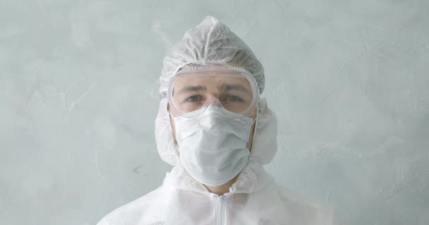 Portrét lékaře v masce a ochranném oblečení v pandemii koronaviru. — Stock video