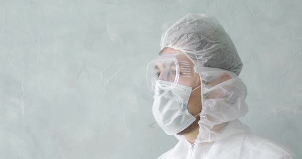 Man doctor in mask and protective suit during coronavirus pandemic, side view. — Stock Video