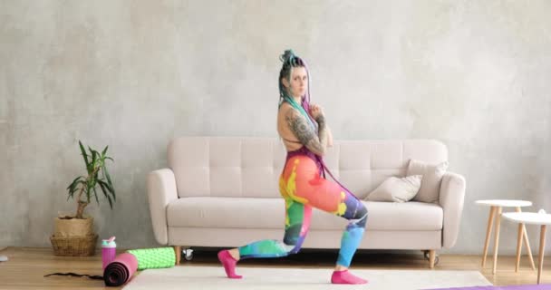 Funny woman with braided hairs is doing lunges at home, sport fitness concept. — Stock Video