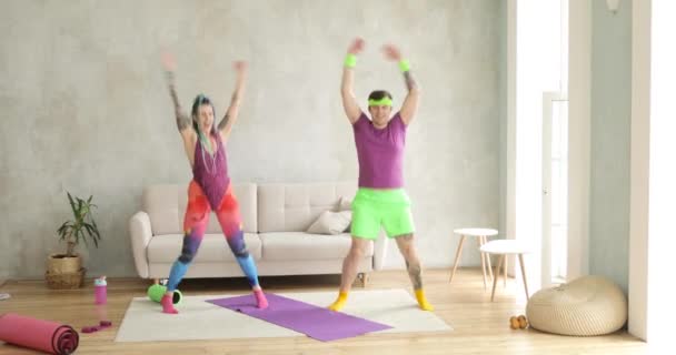 Mand og kvinde gør hoppe aerobe fitness øvelser derhjemme i stuen. – Stock-video