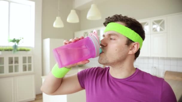 O homem está bebendo água da garrafa após o treinamento e derramando seu rosto e corpo . — Vídeo de Stock