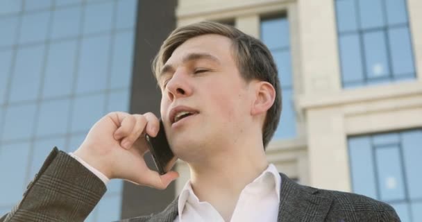 Портрет бізнесмена, який розмовляє на смартфоні в центрі міста біля офісної будівлі . — стокове відео