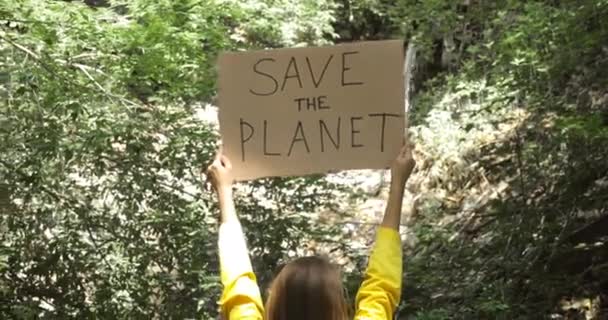 Mãos de mulher voluntária perto de tubo de esgoto na floresta com cartaz salvar o planeta . — Vídeo de Stock