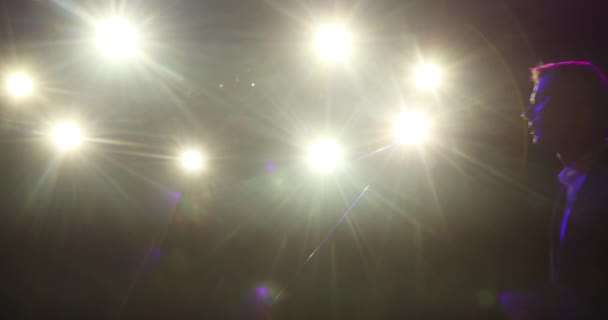 Sahnede sahne ışıkları altında duran komedyen konuşan mikrofon silueti.. — Stok video