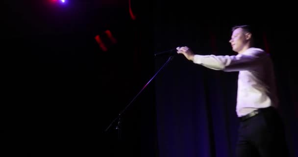 Muž vstát komik mluví vtipné vtipy v mikrofonu stojící na jevišti. — Stock video
