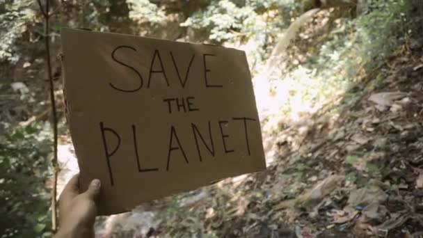 Affisch rädda planeten i mans hand nära röret med avlopp i skogen. — Stockvideo
