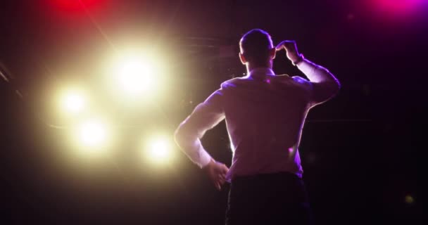 Hombre cantante cantando una canción en el escenario en concierto en la oscuridad en el centro de atención, vista trasera . — Vídeos de Stock