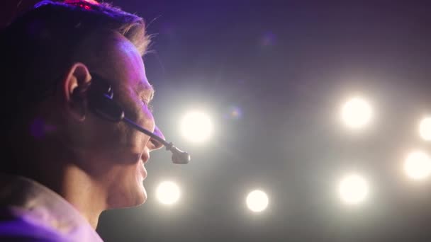 Man högtalare känslomässigt sett headset mikrofon i spotlights, sidovy. — Stockvideo