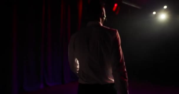 Showman is taking a stage and entertaining audience in spotlights, back view. — Stock Video